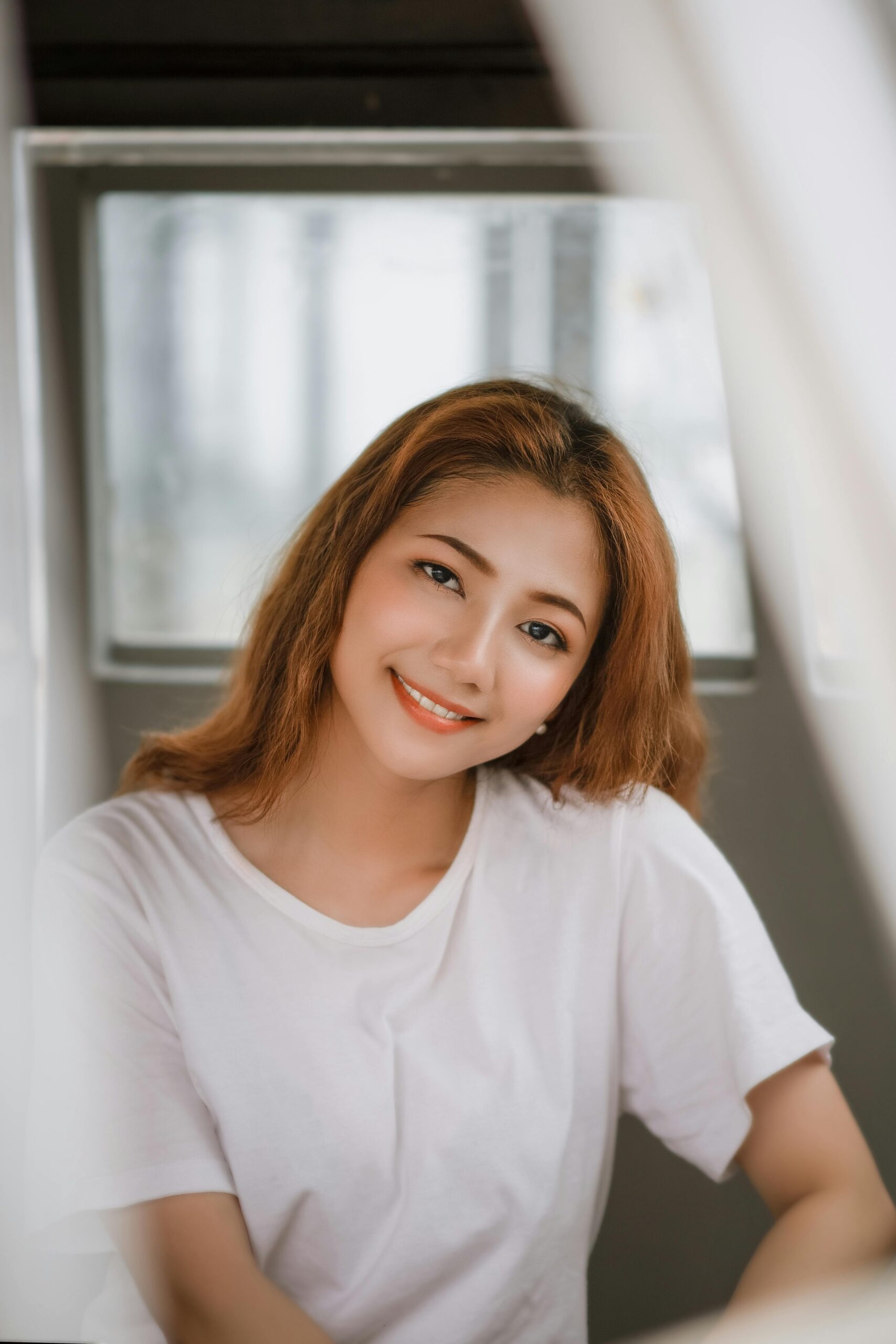 Portrait of a young woman smiling in a relaxed indoor setting.